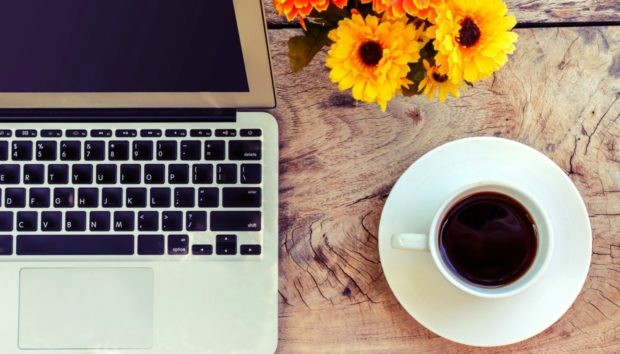 Cup of coffee and laptop on wooden table, vintage style
