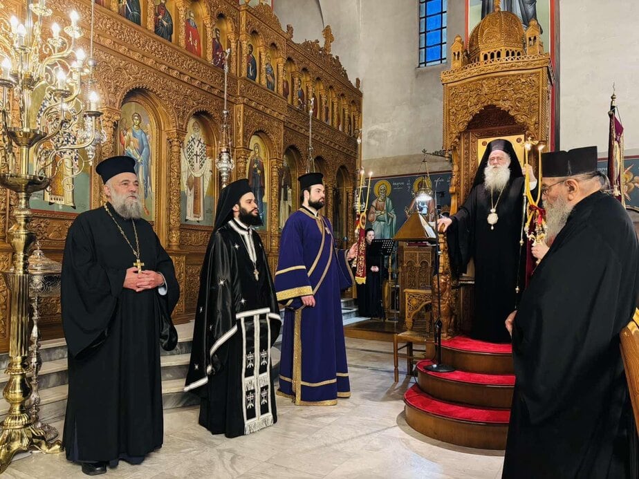 Ornate Orthodox church interior with clergy and religious icons during a ceremony.