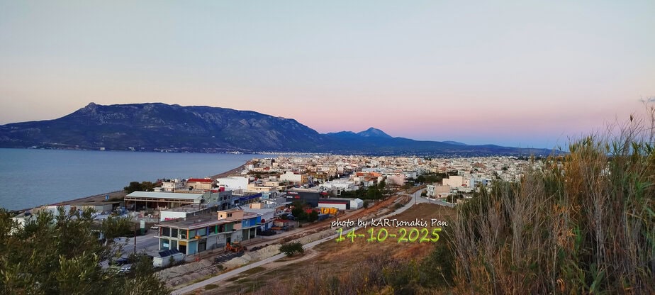 EKorinthos cityscape with mountains and coastline at sunset.