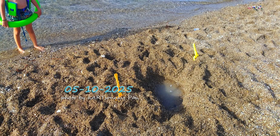 Child's sandcastle with water puddle on beach, date 05-10-2023.
